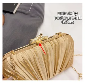 Detail of champagne pleated evening bag showing branch-shaped metal clasp and chain