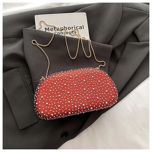 Detail der roten Glitzer-Clutch mit silbernen Nieten und Goldkette auf grauem Blazer