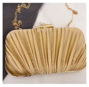 Macro detail of golden pleated evening clutch with shell texture and branch lock