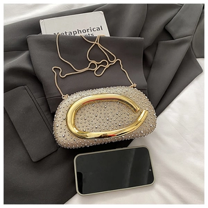 Detailaufnahme der goldenen Abend-Clutch mit Strasssteinen, C-Metallgriff und feiner Kette