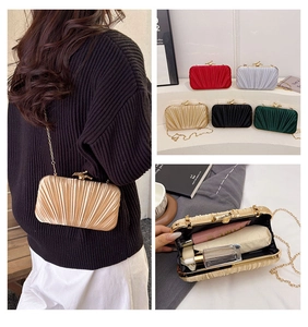 Detail view of pleated clutch bag featuring bird clasp and internal storage capacity