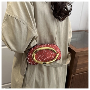 Detail der roten Strass-Clutch mit goldener C-Schnalle und beigem Trenchcoat-Look