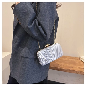 Detail of silver pleated silk clutch bag with gold branch clasp and elegant chain strap