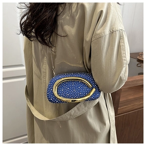 Blaue Abendtasche mit Strassbesatz und goldener C-Schnalle getragen über einem Trenchcoat