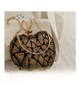Detailed view of heart-shaped evening bag featuring gold sequins and metal chain strap