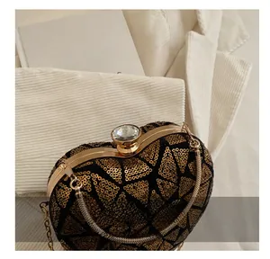 Macro view of a gold sequin heart-shaped evening bag with a crystal clasp and metal chain
