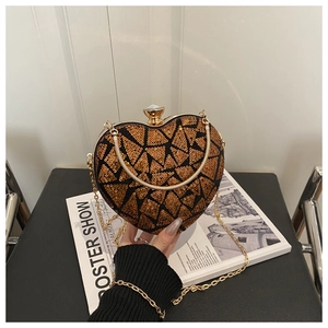 Detailed view of heart-shaped sequin evening bag with gold chain and rhinestone clasp