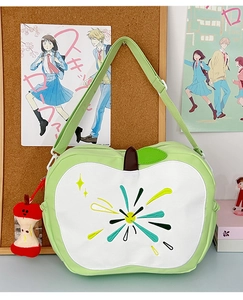 Close-up of apple-shaped green bag with colorful embroidery and plush core pendant