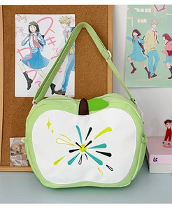 Detail of light green apple-shaped bag featuring heart embroidery and adjustable strap