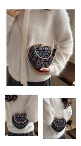 Macro detail of heart-shaped sequin evening bag with gold chain strap and metal clasp