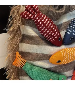 Close-up of striped woven tote bag featuring colorful fish charms and fringe tassels