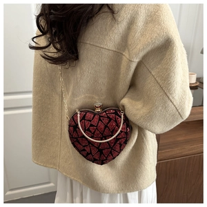 Sequin heart-shaped clutch with red-black patterns and gold chain shown on model