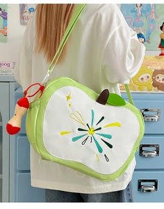 Detailed view of apple-shaped shoulder bag with embroidery and plush charm accessory