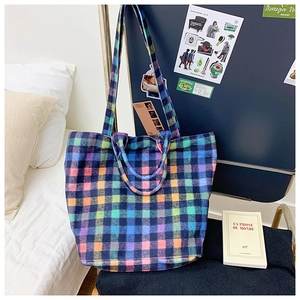 Close-up of rainbow plaid woolen fabric texture and stitching on large bucket bag