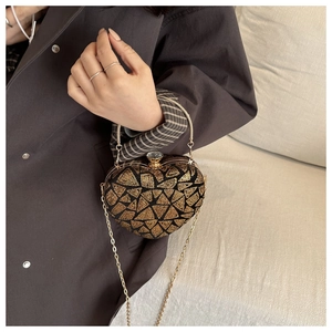 Detail of heart-shaped evening bag with gold geometric sequins and metallic handle