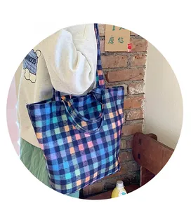 Detail of colorful plaid woven tote bag shown on a model in a cozy indoor setting