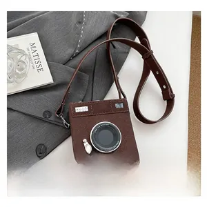 Detail view of camera-shaped brown crossbody bag on grey suit with artistic props