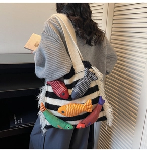 Detail of striped knit tote bag with colorful plush fish accents and white tassel fringe