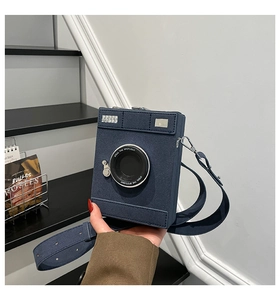 Detail of camera-shaped crossbody bag in dark blue suede with silver metal buckle