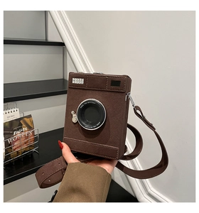 Close-up of camera-shaped crossbody bag featuring textured brown suede and lens detailing