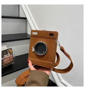Close-up of vintage camera-shaped crossbody bag with Steal The Spotlight text on lens