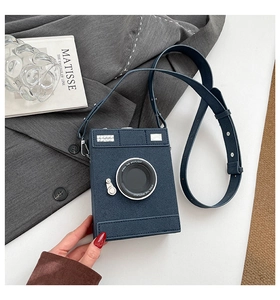 Detail of camera-shaped crossbody bag with lens texture and adjustable shoulder strap