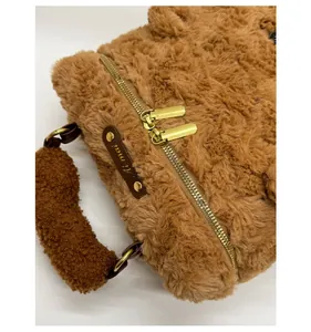 Detail-Makroansicht der goldenen Doppelreißverschlüsse und weichen braunen Plüschtasche