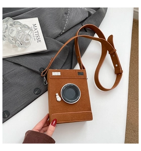 Detail of camera-shaped brown suede crossbody bag with Steal The Spotlight text