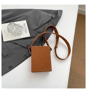 Close-up of caramel suede camera crossbody bag with adjustable strap on desk