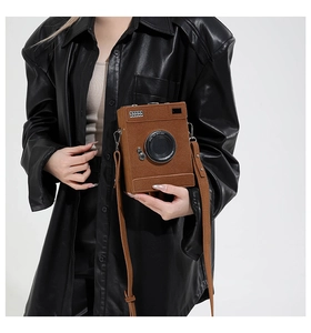 Detailed view of brown camera-shaped creative crossbody bag with suede texture
