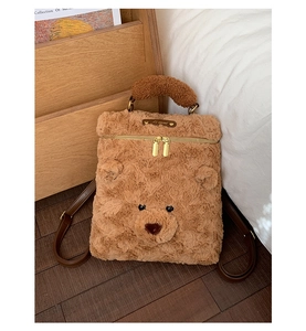 Detail eines süßen braunen Plüschbär-Rucksacks mit Metall-Logo und verstellbaren Trägern