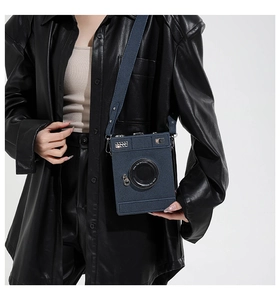 Detail of creative camera-shaped crossbody bag with vintage lens and decorative sequins
