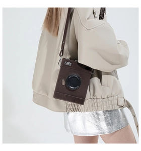 Rear view of creative camera-shaped brown leather crossbody bag styled with a leather jacket
