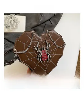 Detail of heart-shaped brown bag with rhinestone spider and metallic chain strap