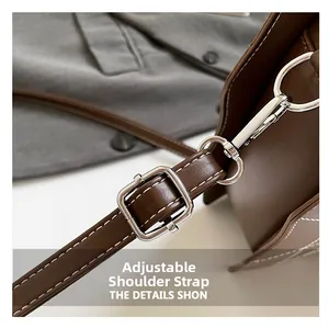 Detail view of coffee leather bag featuring adjustable strap with silver buckle and stitching