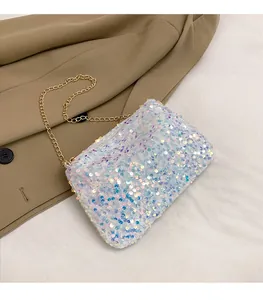 Close-up of sparkling white sequin crossbody bag with gold chain strap on a blazer