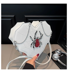 Detail der weißen Herz-Tasche mit Spinnennetz-Naht und rotem Kristall-Spinnen-Anhänger