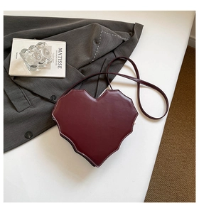 Detail der burgunderroten herzförmigen Tasche mit weißen Kontrastnähten und schmalem Riemen