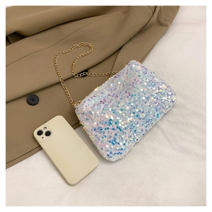 Detail view of white sequin chain bag next to a smartphone for size comparison