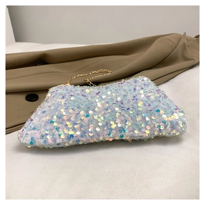 Macro detail of shimmering iridescent sequins and fine gold chain strap on small clutch bag