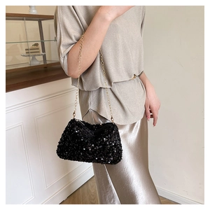 Close-up of elegant black sequin handbag with a fine gold chain strap and glossy finish