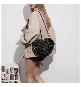 Gothic heart-shaped crossbody bag with spider web embroidery worn by a model