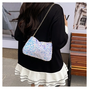 Close-up of iridescent sequins and gold chain strap on a small crossbody bag worn by a model