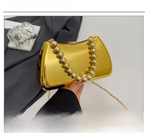 Close-up of a gold mirror acrylic clutch with beaded handle and fine metal chain strap