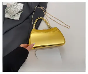 Macro detail of gold mirrored evening bag showing bead handle and size compared to phone