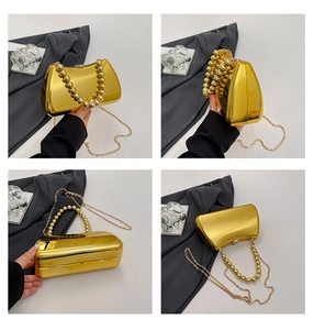 Macro view of gold mirror finish evening clutch with pearl handle and metal chain