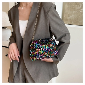 Detail of colorful sequin crossbody bag with gold chain strap on a grey suit jacket