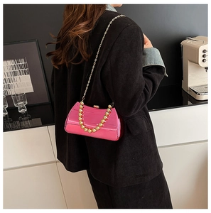 Detailed back view of a metallic rose pink clutch bag with gold beaded handle and chain