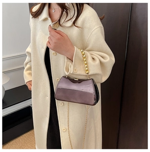 Close-up of purple metallic clutch featuring large gold bead handle and slim chain strap
