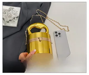 Detail of cylindrical gold acrylic evening bag with Mickey-shaped metal clasp and chain